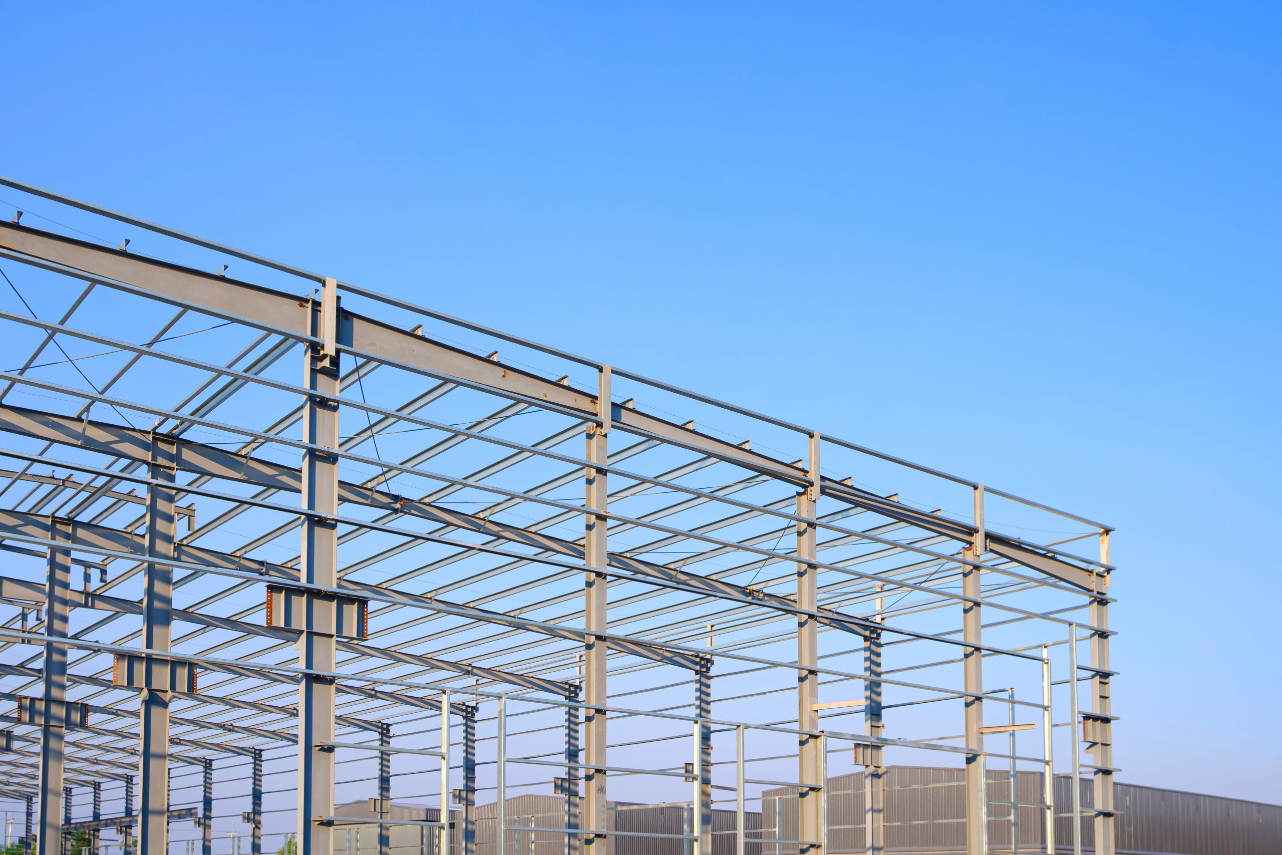 metal-framework-modern-industrial-buildings-construction-site-against-blue-sky-background (1) Acélszerkezetű csarnok vázszerkezete kék ég előtt